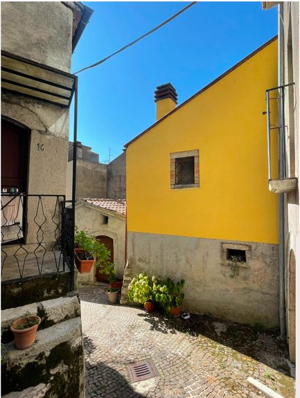 Via Garibaldi a Pizzone, con una casa gialla e i vasi di fiori